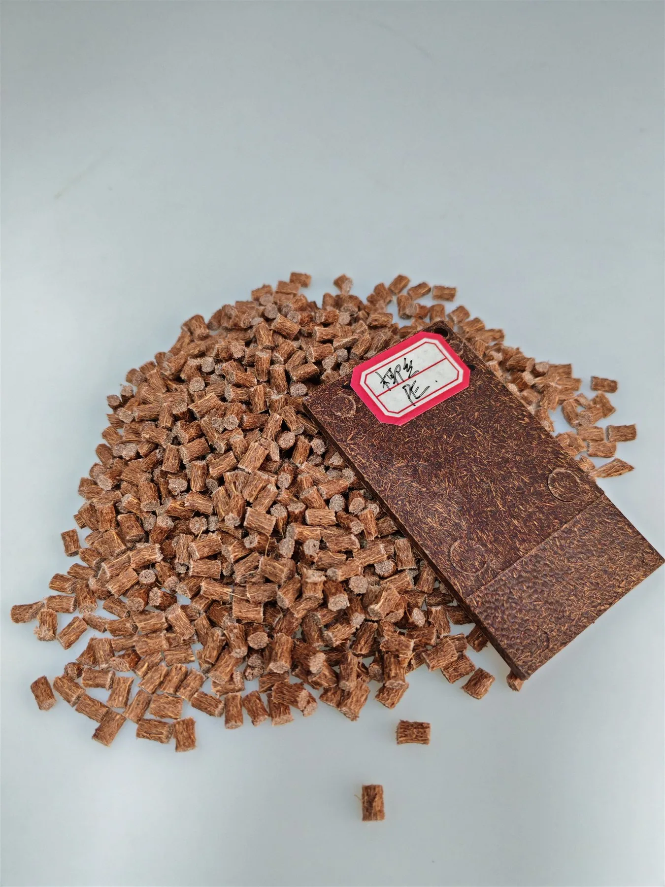 Deep-brown coconut fiber PE masterbatch pellets with a molded sample plaque